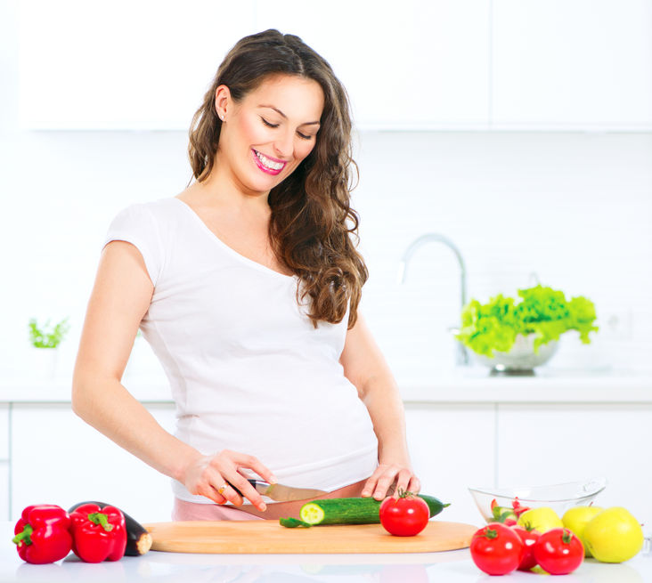 35560978 - pregnant young woman cooking vegetables. healthy food