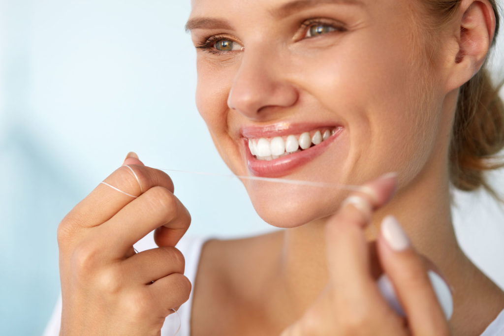 61732293 - dental hygiene. closeup of beautiful happy smiling woman with beauty face and perfect smile cleaning, flossing healthy white teeth using floss. oral health, tooth care concept. high resolution image